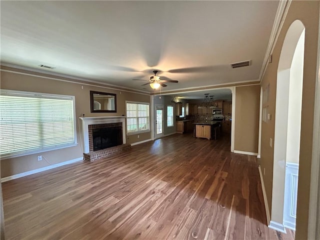 1038 Island View Ct, Buford, GA 30518 - unfurnished living room featuring ornamental molding, arched walkways, a ceiling fan, dark wood-style floors, and a fireplace