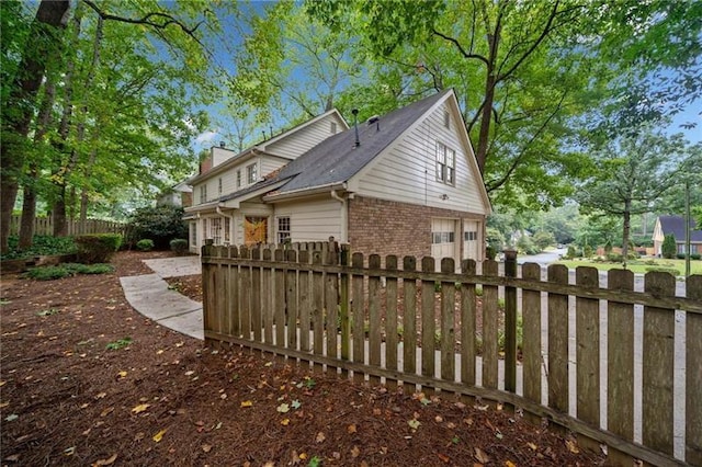 view of property exterior with fence private yard, a chimney, and brick siding