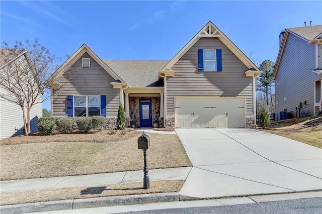 craftsman-style home with a garage, concrete driveway, central AC, and stone siding