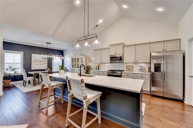 kitchen with appliances with stainless steel finishes, a breakfast bar, light countertops, light wood-style floors, and a sink