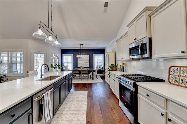 kitchen with appliances with stainless steel finishes, light countertops, visible vents, and a sink