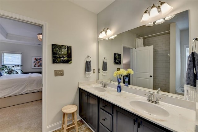 ensuite bathroom featuring double vanity, ensuite bath, baseboards, and a sink