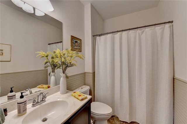 full bath featuring a wainscoted wall, curtained shower, vanity, and toilet