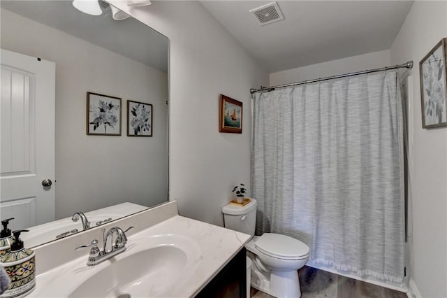 bathroom featuring toilet, wood finished floors, vanity, and visible vents