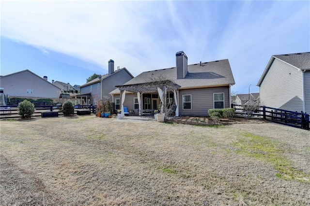 back of house with a yard, a chimney, a patio area, fence, and a pergola