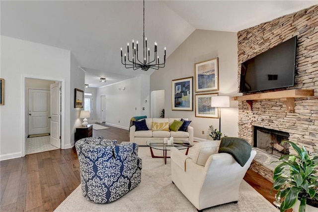 living room with high vaulted ceiling, a fireplace, wood finished floors, baseboards, and an inviting chandelier