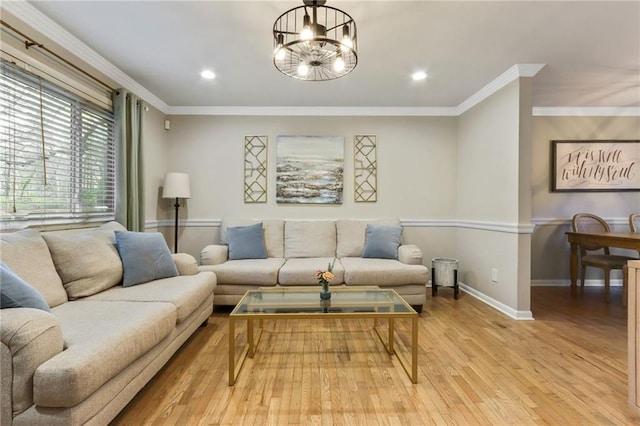 living room with light hardwood / wood-style flooring, ornamental molding, and a notable chandelier