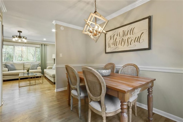 dining space with hardwood / wood-style flooring, an inviting chandelier, and ornamental molding