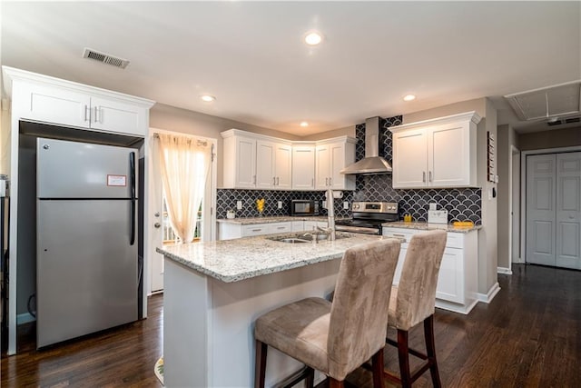 kitchen with visible vents, white cabinetry, appliances with stainless steel finishes, wall chimney range hood, and dark wood-style flooring