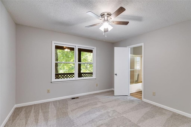 unfurnished room featuring ceiling fan, light colored carpet, and a textured ceiling