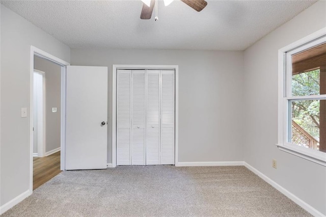 unfurnished bedroom featuring ceiling fan, light colored carpet, a textured ceiling, and a closet