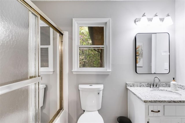 full bathroom with vanity, bath / shower combo with glass door, and toilet