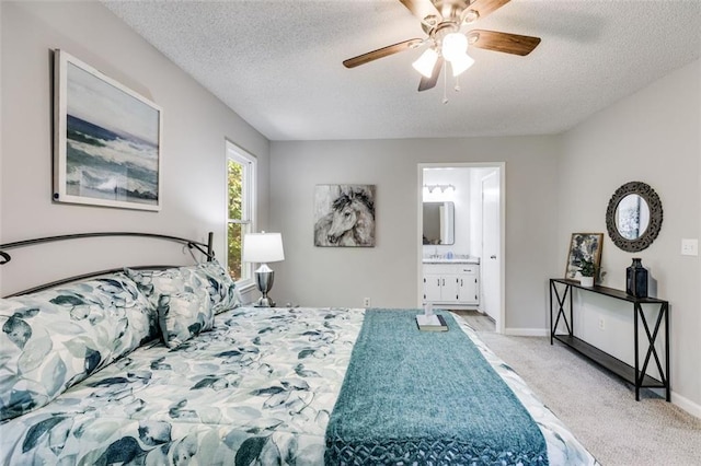 bedroom featuring ceiling fan, ensuite bath, light carpet, and a textured ceiling