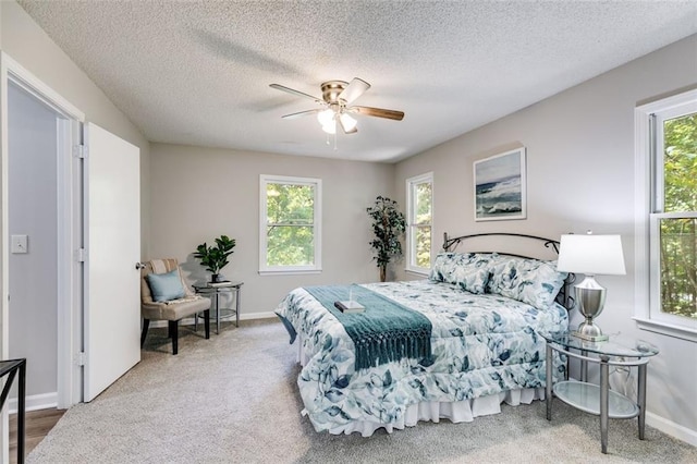 bedroom featuring multiple windows, a textured ceiling, ceiling fan, and carpet