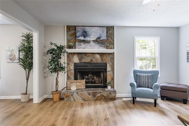 living area featuring a fireplace, light hardwood / wood-style floors, and a textured ceiling