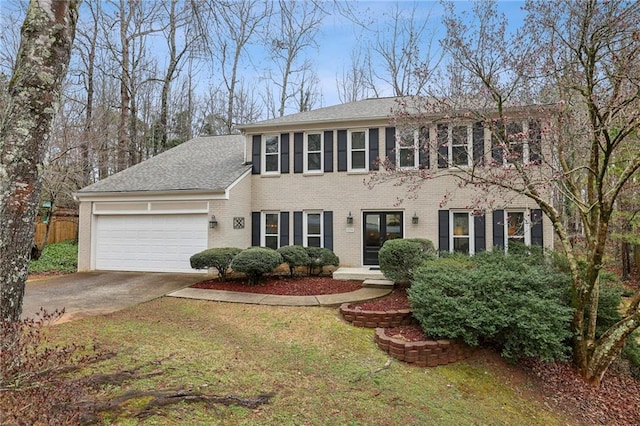 colonial house with a garage, brick siding, concrete driveway, roof with shingles, and a front yard