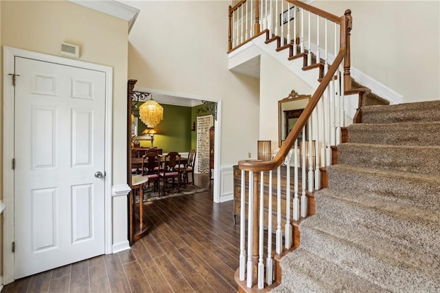 stairs featuring a high ceiling and wood finished floors