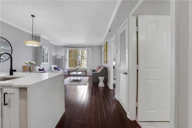 interior space featuring crown molding, dark hardwood / wood-style floors, pendant lighting, and sink