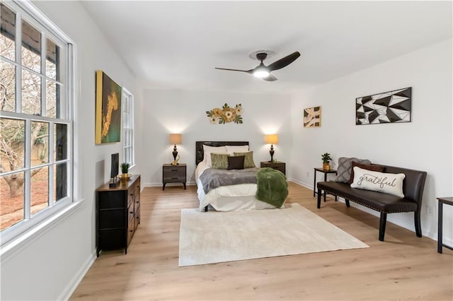 bedroom featuring ceiling fan, light hardwood / wood-style floors, and multiple windows