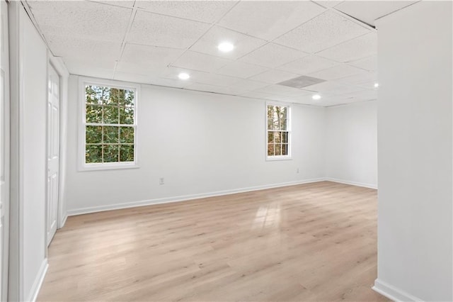 spare room with a paneled ceiling, plenty of natural light, and light wood-type flooring