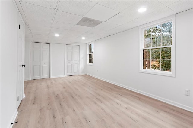 spare room featuring a drop ceiling, light hardwood / wood-style flooring, and plenty of natural light