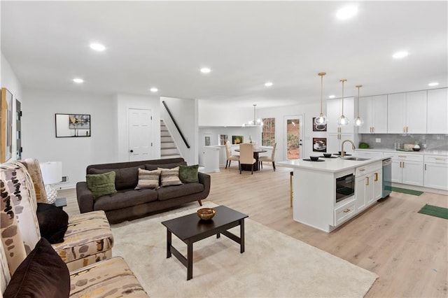 living room with a chandelier, sink, and light hardwood / wood-style flooring