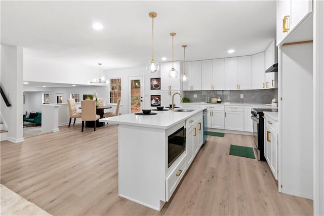 kitchen featuring built in microwave, hanging light fixtures, electric range oven, and white cabinets