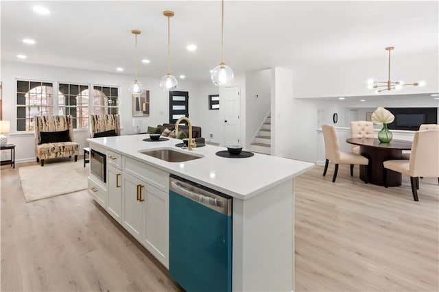 kitchen featuring sink, white cabinetry, a center island with sink, stainless steel dishwasher, and pendant lighting