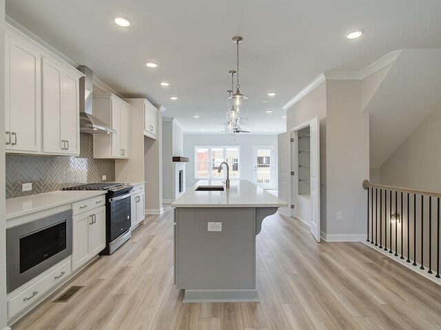 1976 Deco Dr, Kennesaw, GA 30144 - kitchen featuring wall chimney range hood, light countertops, white cabinetry, a sink, and appliances with stainless steel finishes