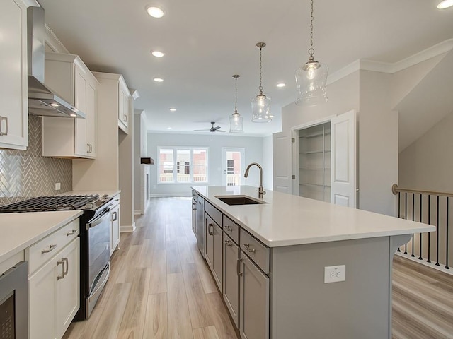 1976 Deco Dr, Kennesaw, GA 30144 - kitchen with wall chimney range hood, recessed lighting, stainless steel range with gas stovetop, a sink, and light wood finished floors