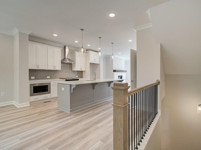 1976 Deco Dr, Kennesaw, GA 30144 - kitchen with wall chimney range hood, white cabinets, decorative backsplash, and a breakfast bar area