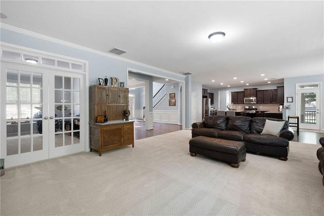 carpeted living room featuring french doors and ornamental molding