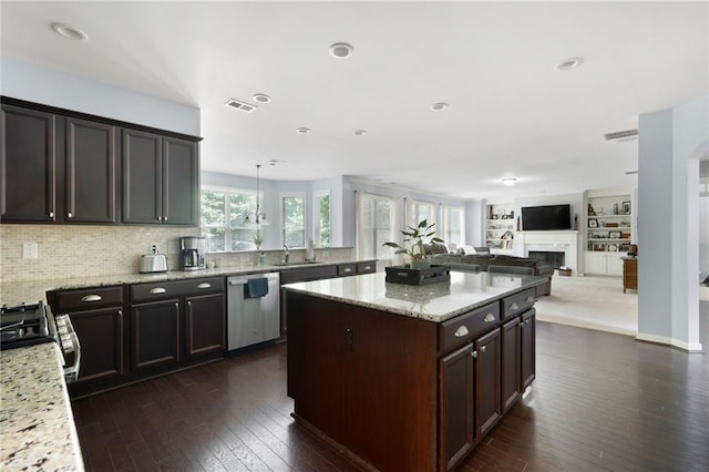 kitchen with light stone countertops, range, hanging light fixtures, stainless steel dishwasher, and dark brown cabinets