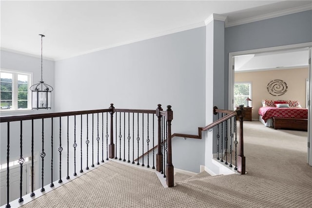 hallway with carpet floors, ornamental molding, and an inviting chandelier