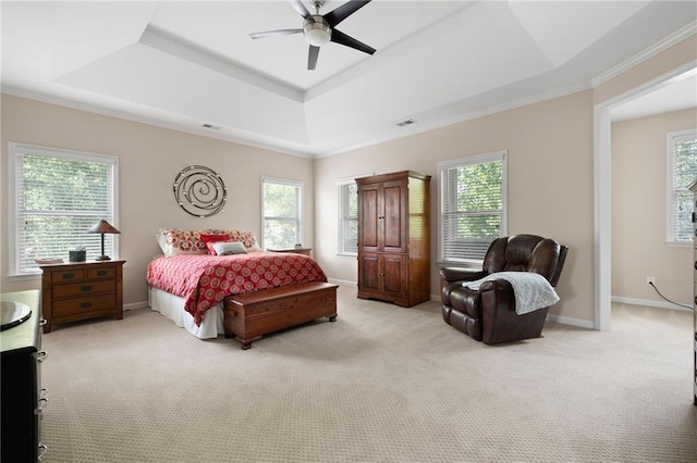 bedroom with ceiling fan, light carpet, and a tray ceiling