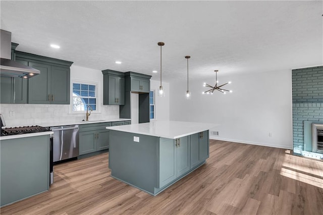 kitchen with sink, dishwasher, hanging light fixtures, light hardwood / wood-style flooring, and a kitchen island