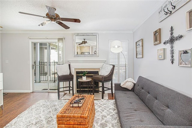 living room with hardwood / wood-style flooring, a textured ceiling, crown molding, and ceiling fan