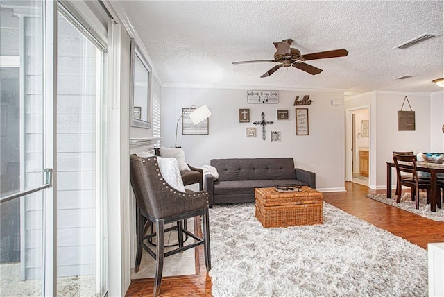 living room featuring a textured ceiling, ceiling fan, crown molding, and hardwood / wood-style floors