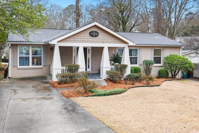 view of front of property with covered porch, brick siding, and roof with shingles