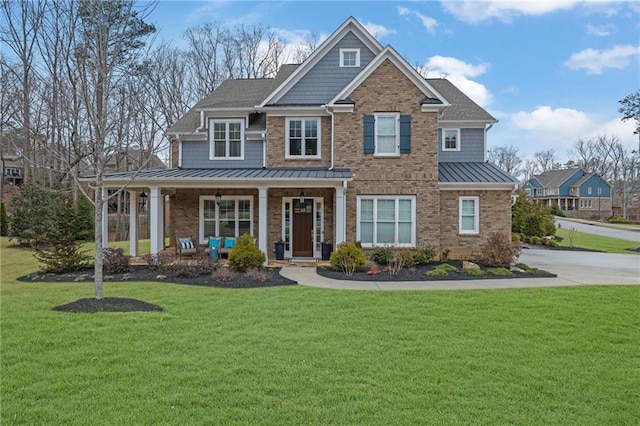 view of front facade with brick siding, covered porch, a front yard, a standing seam roof, and metal roof