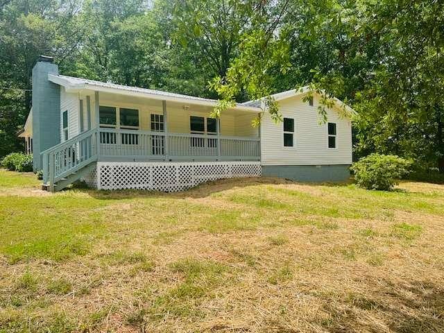 view of front of home featuring a front lawn, a porch, crawl space, a chimney, and metal roof