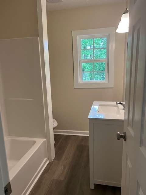 full bath with vanity, baseboards, wood finished floors, and toilet