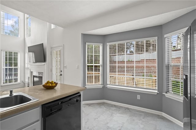 4044 Spring Cove Dr, Duluth, GA 30097 - kitchen with black dishwasher, a sink, light marble finish floors, baseboards, and a glass covered fireplace
