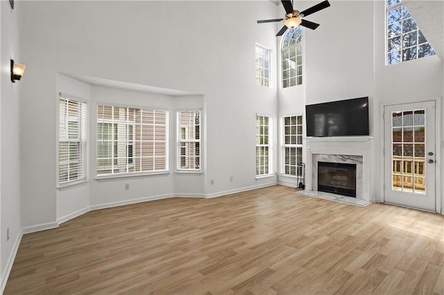4044 Spring Cove Dr, Duluth, GA 30097 - unfurnished living room featuring light wood-style floors, a towering ceiling, a ceiling fan, a high end fireplace, and baseboards