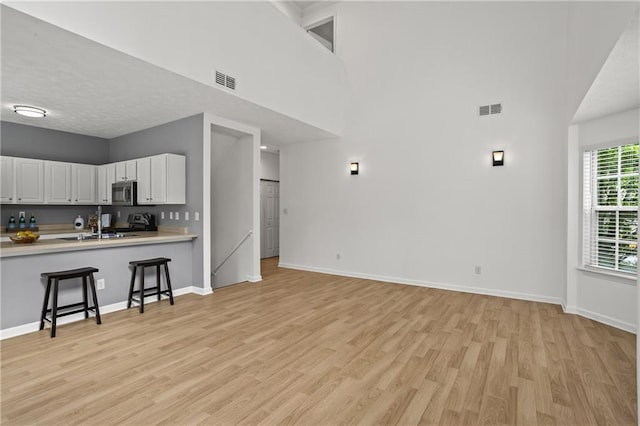 4044 Spring Cove Dr, Duluth, GA 30097 - living room featuring light wood-style flooring, baseboards, and a towering ceiling
