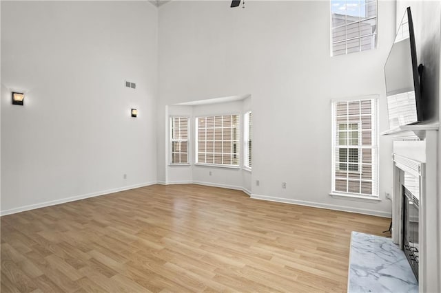 4044 Spring Cove Dr, Duluth, GA 30097 - unfurnished living room featuring a towering ceiling, a fireplace, light wood-type flooring, baseboards, and healthy amount of natural light