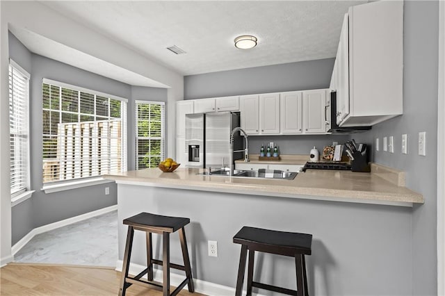 4044 Spring Cove Dr, Duluth, GA 30097 - kitchen with stainless steel refrigerator with ice dispenser, a peninsula, a sink, white cabinetry, and light countertops