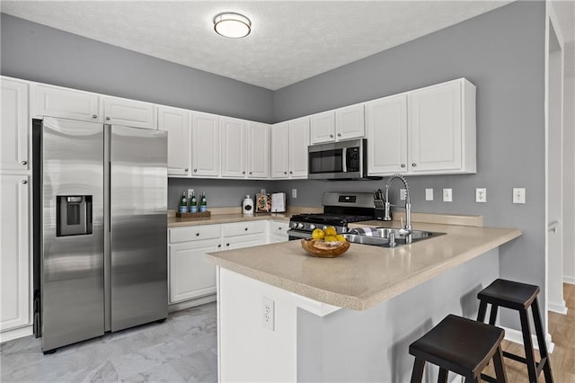 4044 Spring Cove Dr, Duluth, GA 30097 - kitchen featuring appliances with stainless steel finishes, a sink, a peninsula, white cabinetry, and a kitchen bar