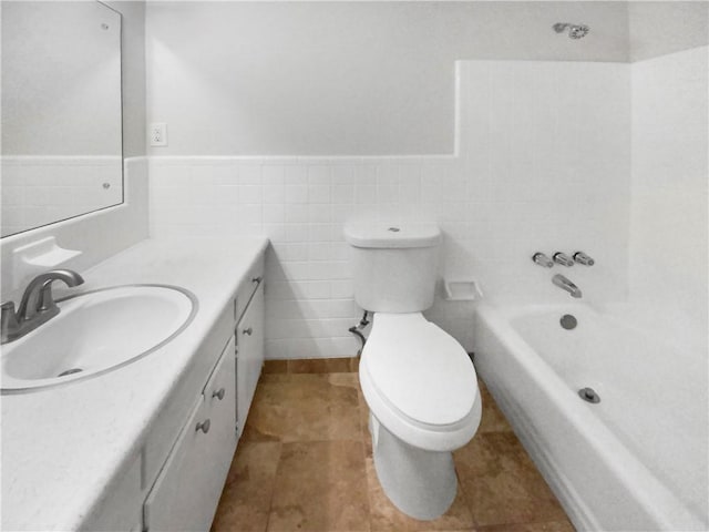 bathroom featuring tile patterned flooring, vanity, toilet, and tile walls