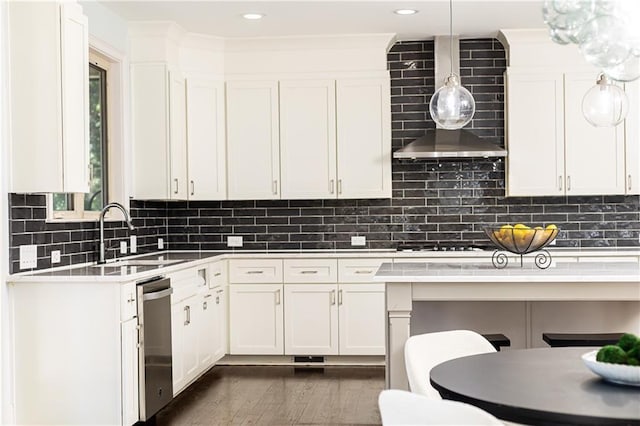 kitchen with wall chimney range hood, pendant lighting, sink, white cabinetry, and gas stovetop